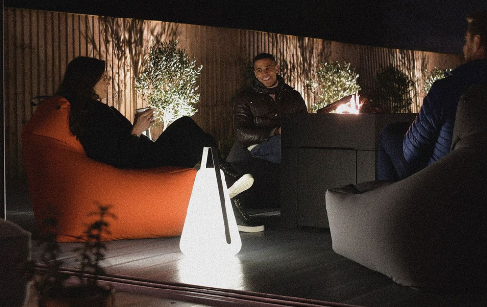 People sat outside on garden beanbags with a large solar light