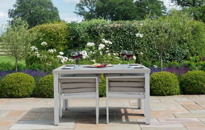 A grey aluminium space saving cube table with the chairs tucked underneath